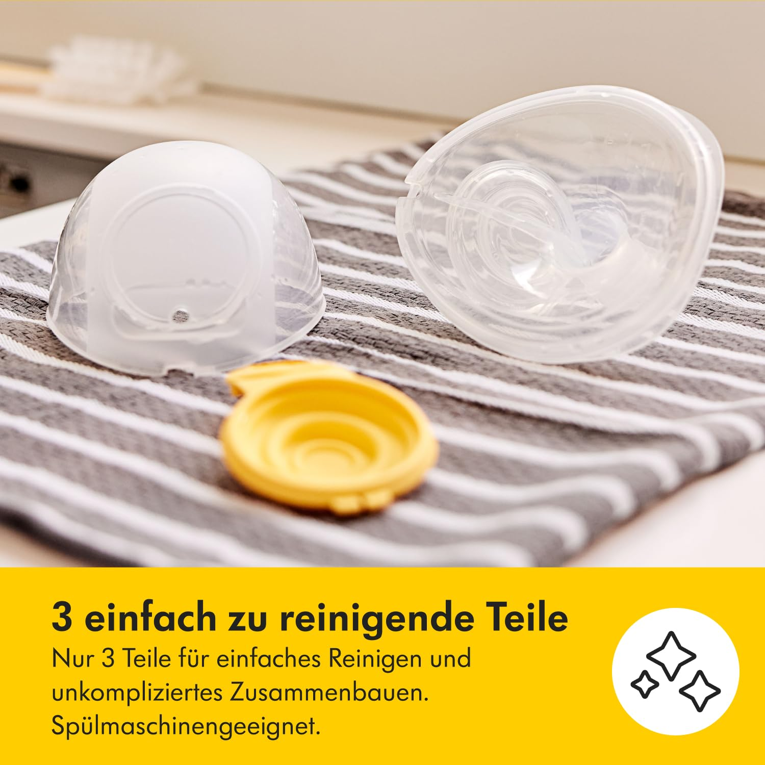 Drei klare Plastikteile einer Brustpumpe liegen auf einem gestreiften Handtuch. Ein gelbes Teil liegt unten. Text auf Deutsch: '3 leicht zu reinigende Teile.'