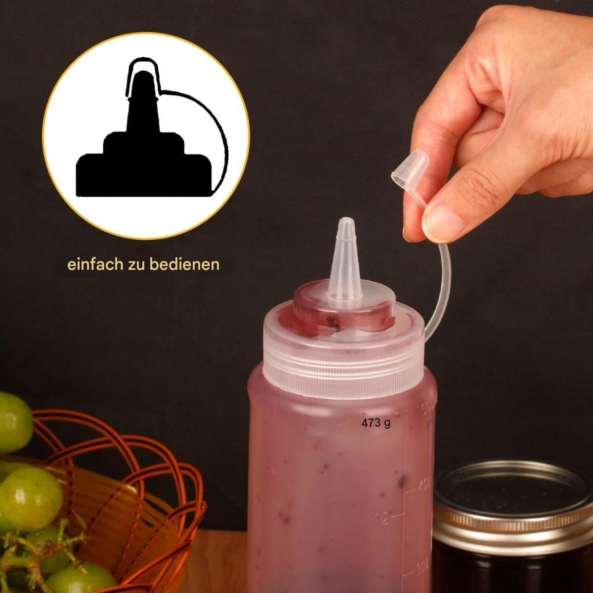 Eine Hand öffnet eine transparente Plastik-Quetschflasche mit roter Flüssigkeit, neben einem Traubenkörbchen und einem Glas.