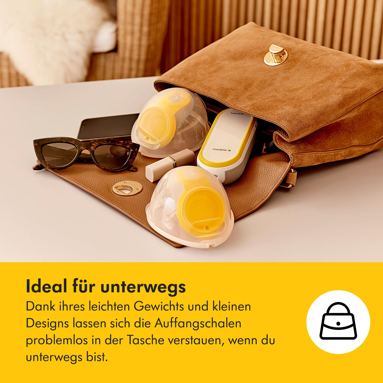 Eine braune, offene Handtasche mit Brustpumpenteilen, Sonnenbrille und Telefon darin. Text unten lautet 'Ideal für unterwegs'.