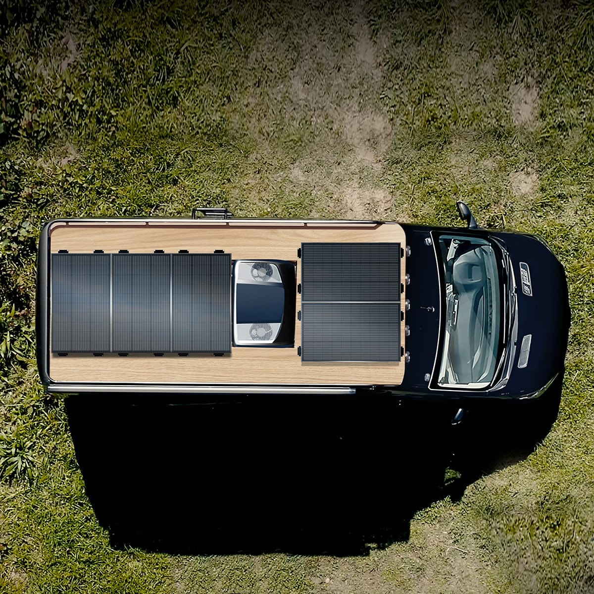 Widok z góry na czarnego vana z panelami słonecznymi na drewnianym dachu, zaparkowanego na trawiastym polu.