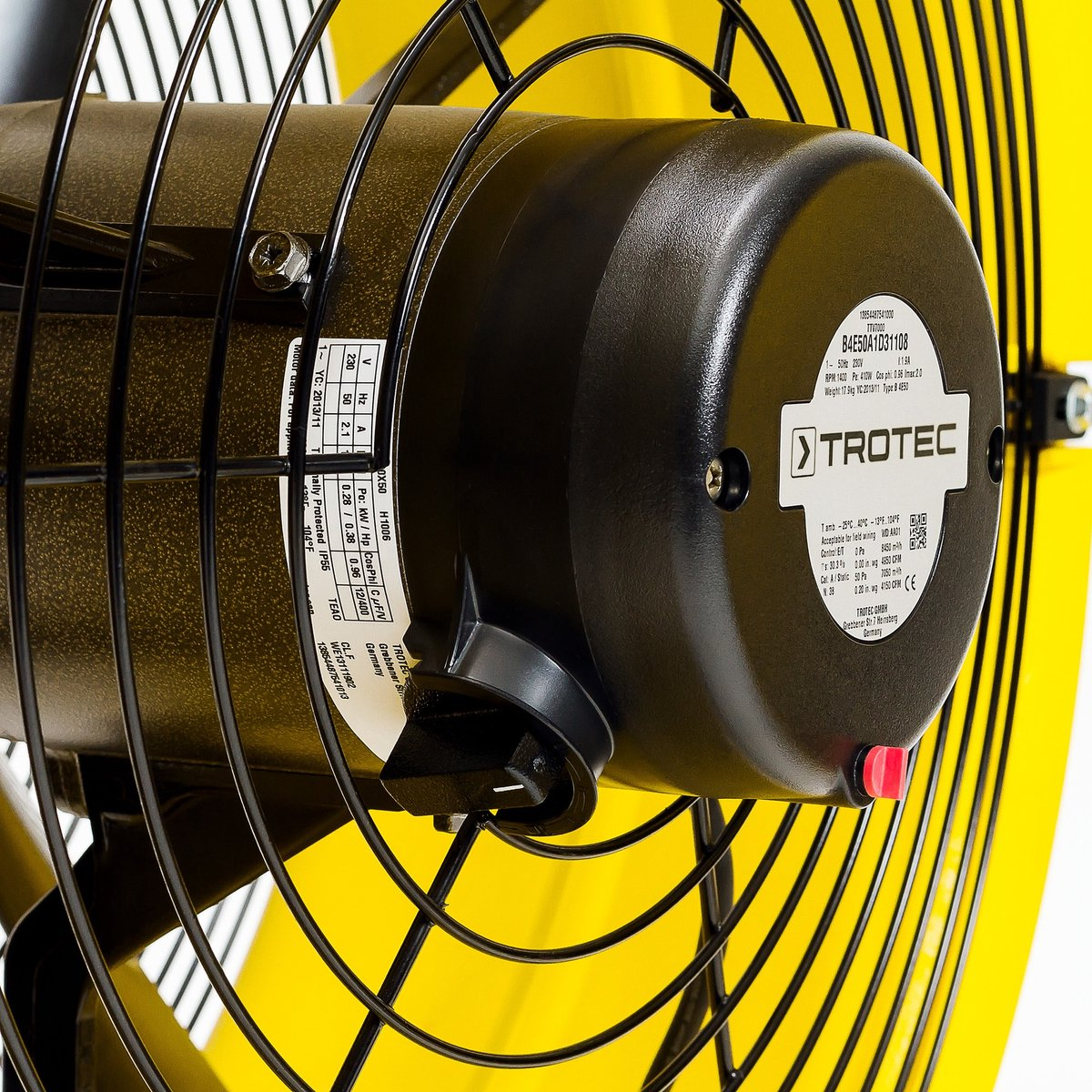 Close-up of a black and yellow fan. The motor has a label and is protected by a black metal grill.