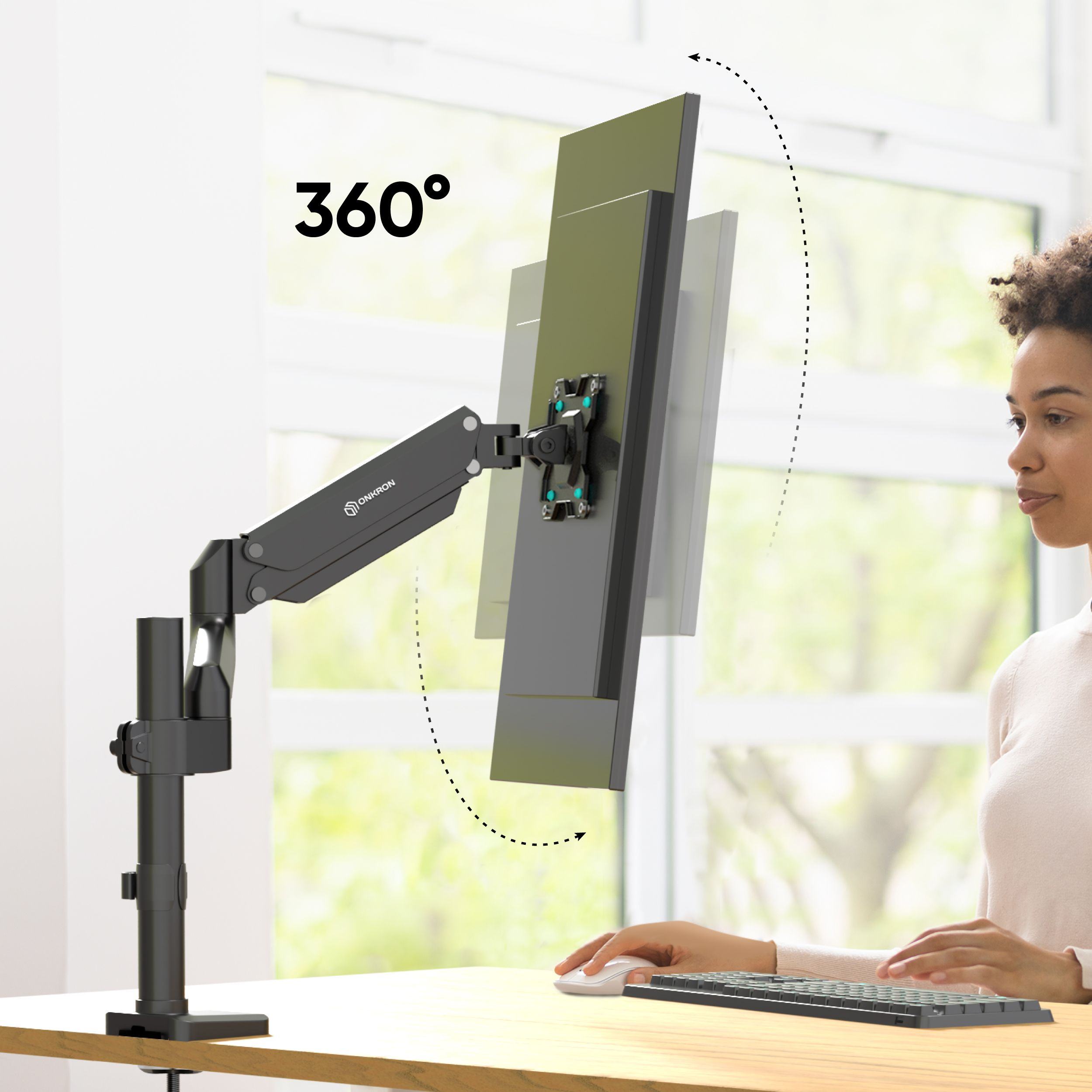 Kobieta korzysta z komputera. Regulowane ramię monitora trzyma ekran. Ekran może obracać się o 360 stopni.
