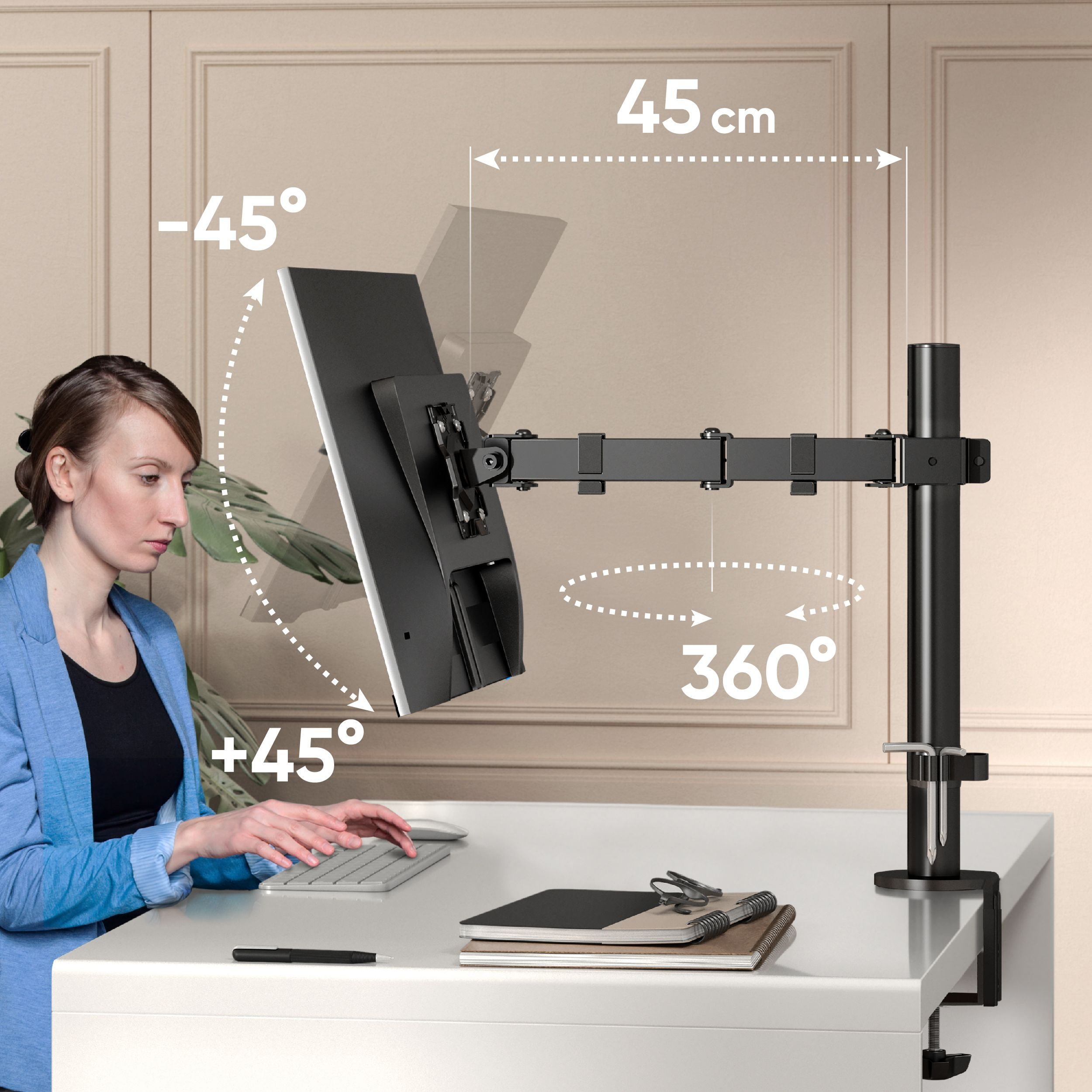 Femme utilisant un ordinateur avec un bras de moniteur. Le moniteur pivote à 360 degrés et s'incline. Un bureau, un stylo et un bloc-notes sont également visibles.
