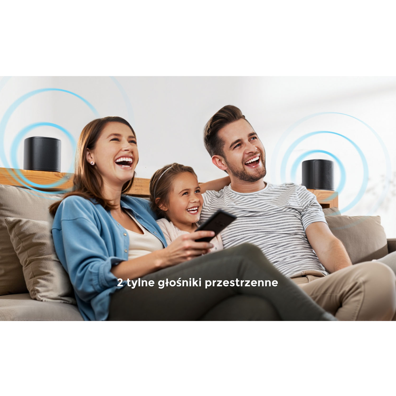 Rodzina ogląda telewizję i się śmieje. Dwa głośniki są za nimi. Tekst mówi: '2 głośniki przestrzenne'.