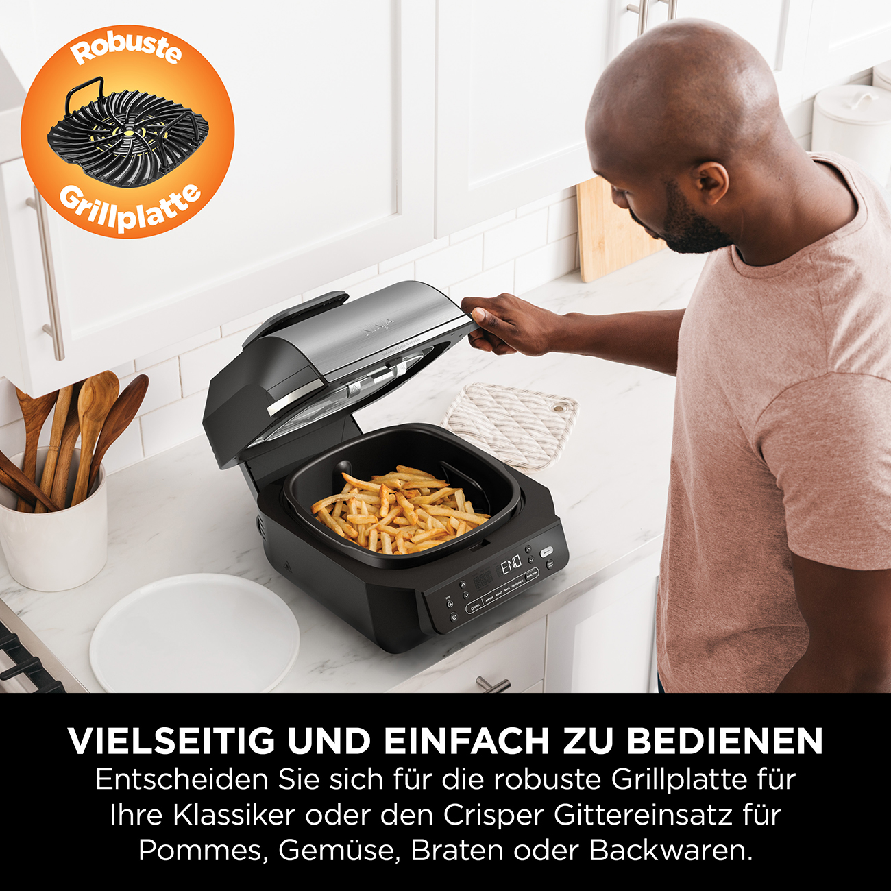 Ein Mann öffnet eine schwarze Heißluftfritteuse mit Pommes Frites. Logo mit „Robuste Grillplatte“. Text darunter: „Vielseitig und einfach zu bedienen“.