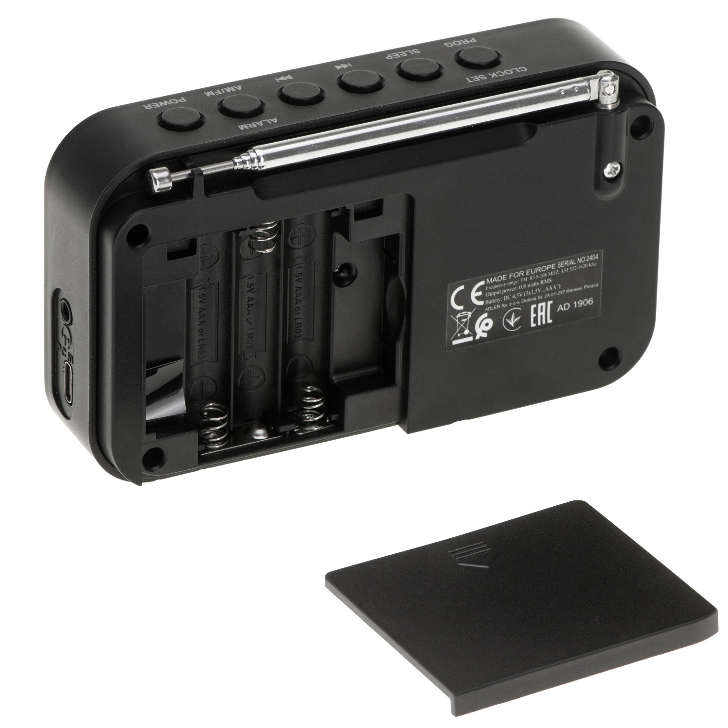Czarny cyfrowy radiobudzik z przyciskami, anteną i otwartą komorą baterii. Pokrywa jest odłączona. Widoczne etykiety i symbole.