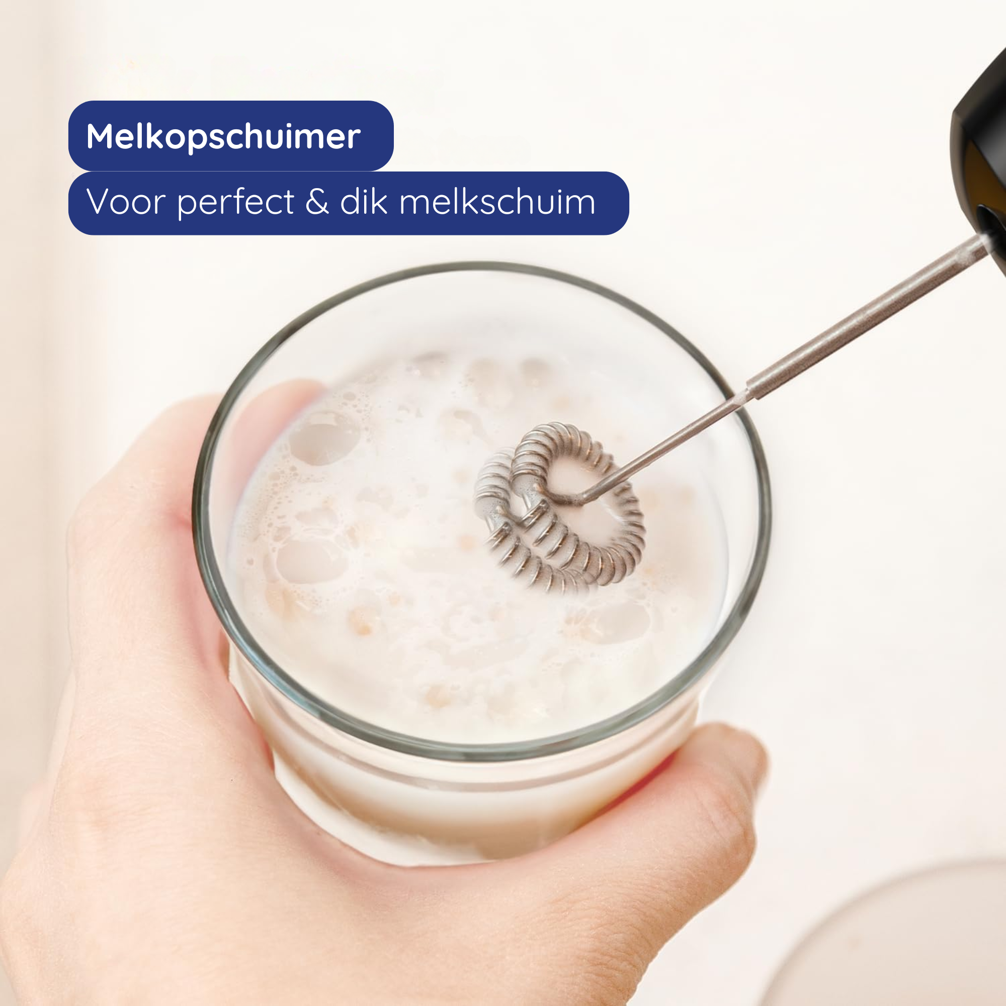 Une main tient un verre de lait avec un mousseur. Le mousseur mélange le lait pour créer de la mousse.