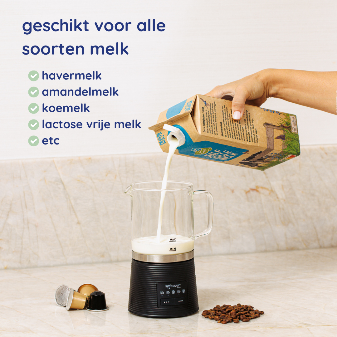 Een hand giet melk uit een karton in een glazen kan op een zwarte basis. Koffiebonen en capsules liggen op het aanrecht.