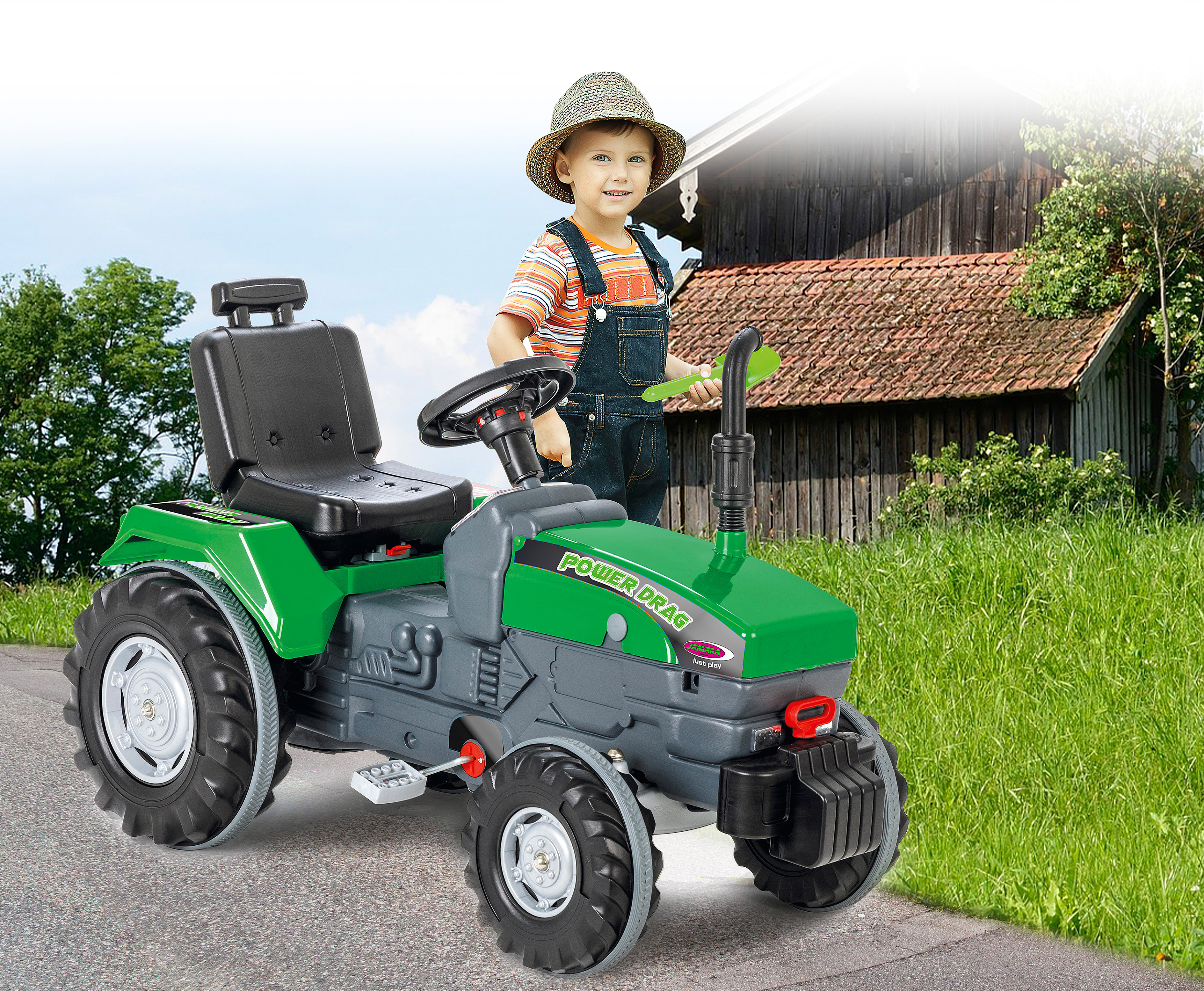 Ein Kind mit Strohhut steht neben einem grünen und grauen Spielzeugtraktor. Eine Scheune und Gras sind im Hintergrund.