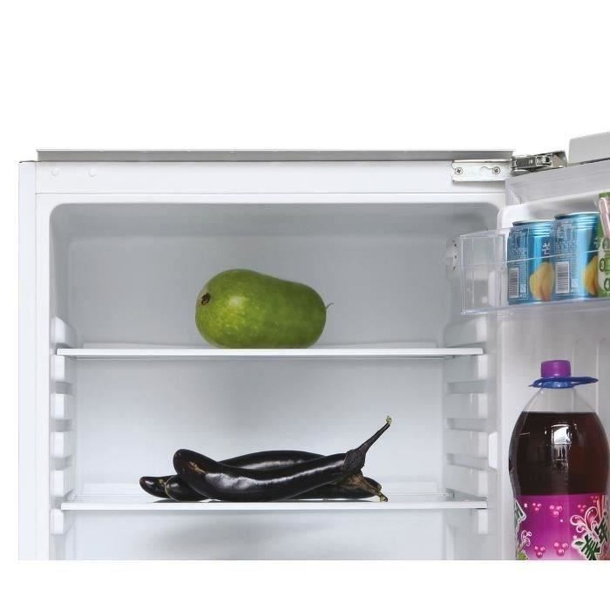 Interno di un frigorifero con un mango verde e due melanzane sugli scaffali. Sono visibili anche lattine e una bottiglia di succo.