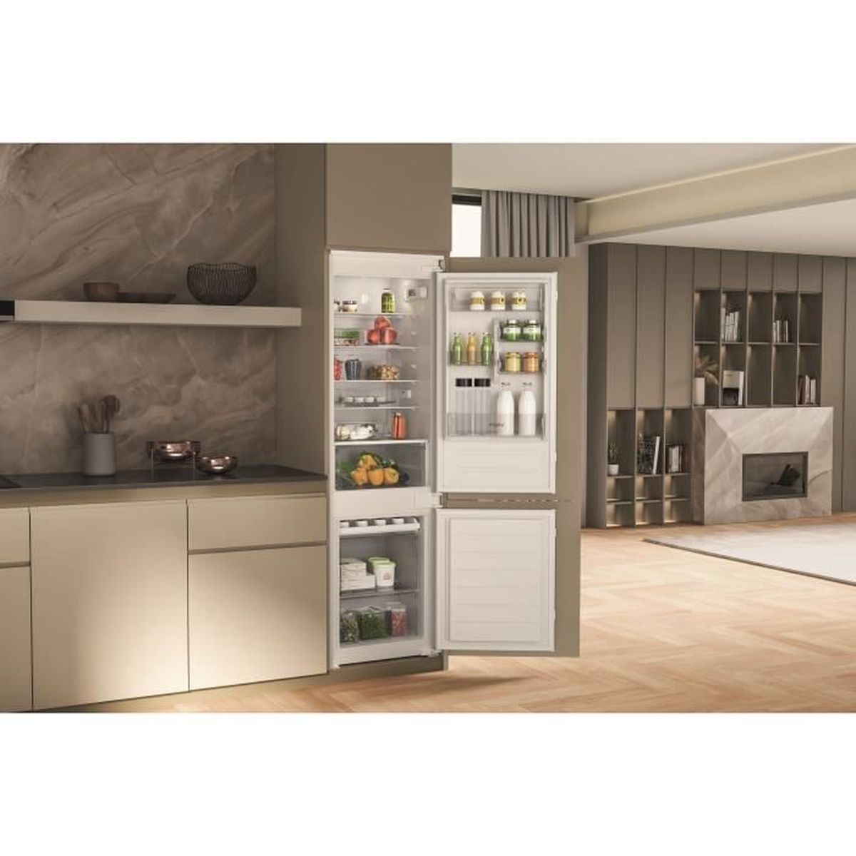 Een open koelkast in een moderne keuken. Hij is gevuld met eten. De keuken heeft lichte houten vloeren en een marmeren open haard.
