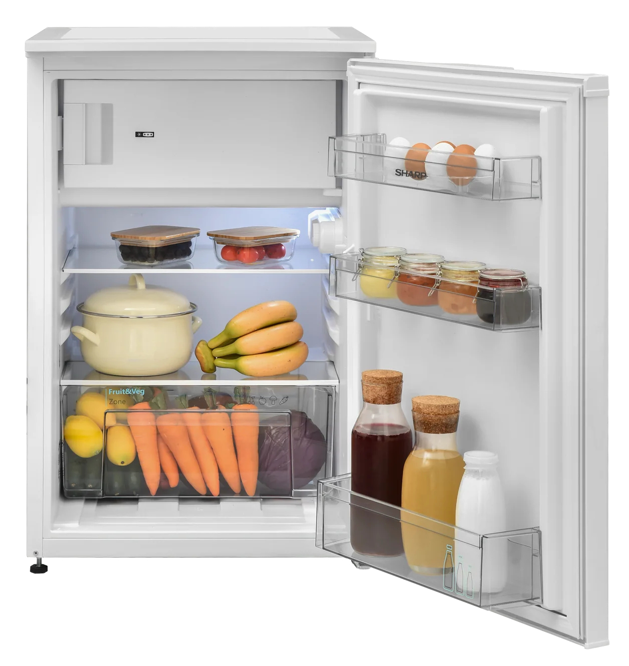 Open fridge filled with food: eggs, jars, drinks, fruits, and vegetables like carrots and lemons. A pot and bananas are visible.