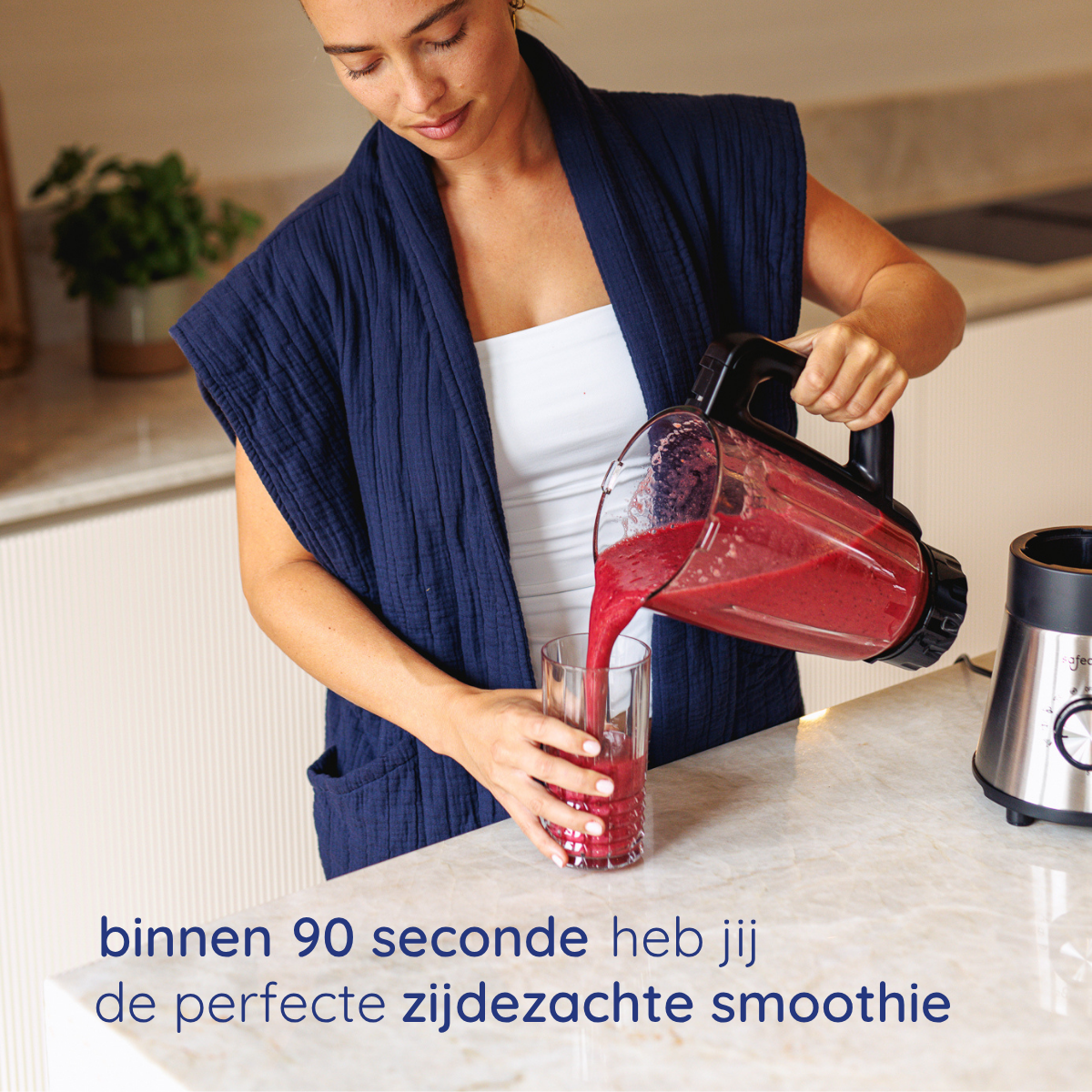 Vrouw schenkt rode smoothie in een glas. Blender en aanrecht zichtbaar. Tekst onder: 'smoothie in 90 seconden'.