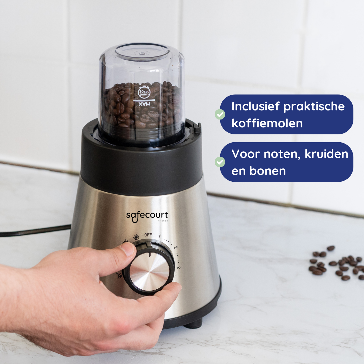 Een zilveren koffiemolen met koffiebonen erin. Een hand draait aan de knop, en een paar bonen liggen op het aanrecht.
