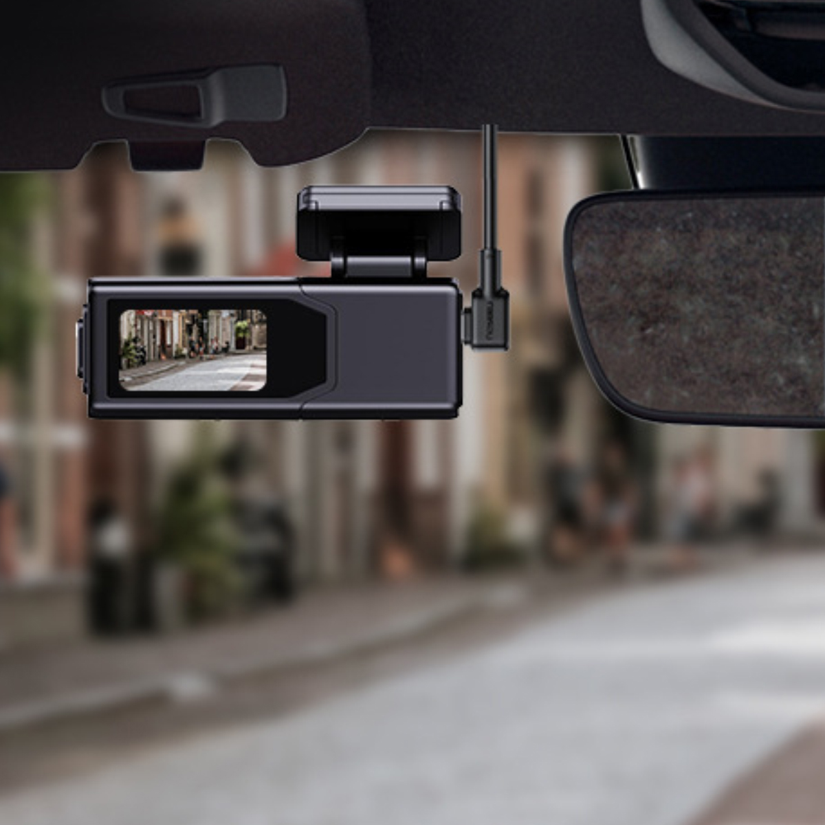 Eine schwarze Dashcam hängt von der Autodecke. Der Bildschirm zeigt eine Straßenszene. Rechts ist ein Rückspiegel.