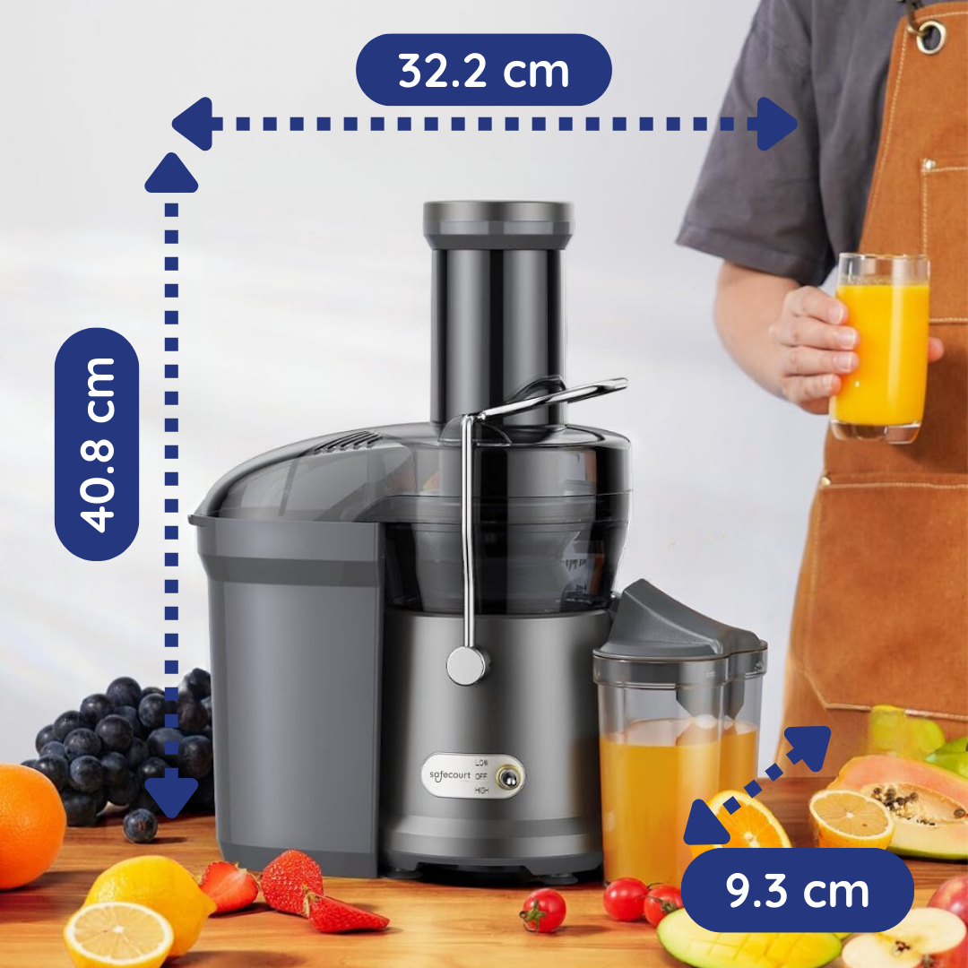 Une centrifugeuse avec un verre de jus tenu par une personne. Des fruits comme des raisins, des fraises et des oranges sont au premier plan.