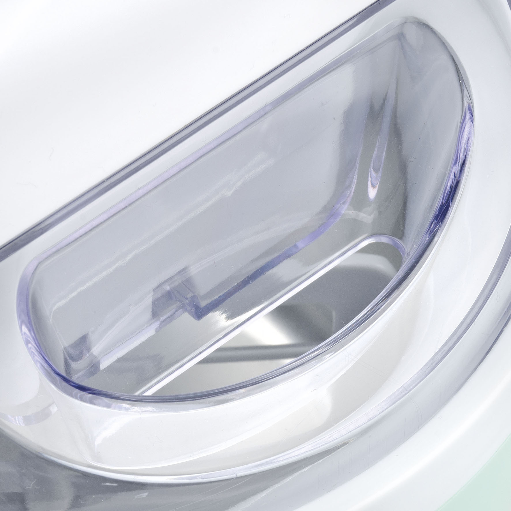 Zbliżenie przezroczystego plastikowego pojemnika z zakrzywionym uchwytem. Pojemnik znajduje się na białej powierzchni.