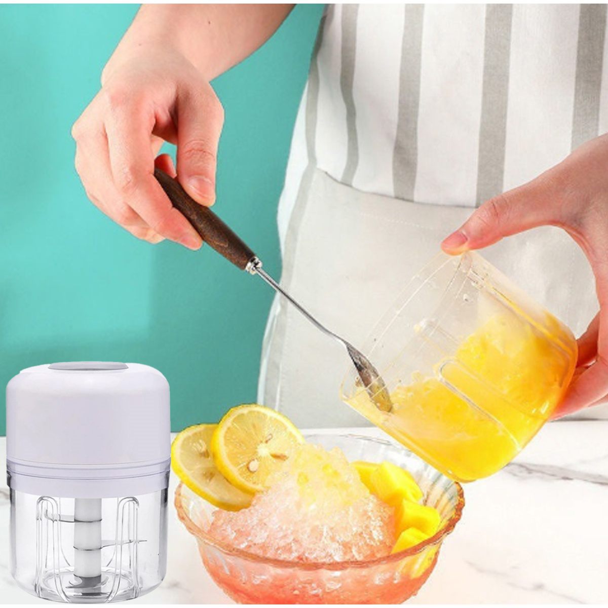 Eine Person gießt gelbe Flüssigkeit aus einem Behälter auf eine Schüssel mit Eis, Zitronenscheiben und Mango. Links steht ein Mixer.