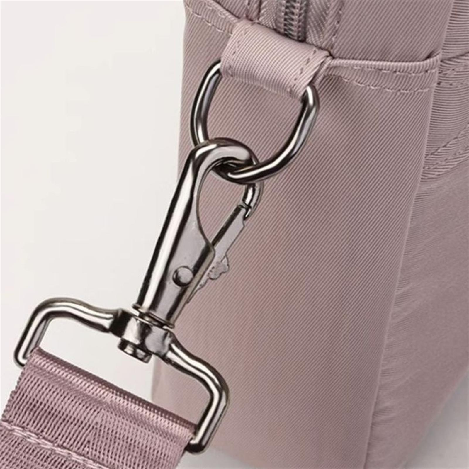 Nahaufnahme eines Metallverschlusses und eines Trägeranschlusses einer Handtasche. Tasche und Riemen sind in gedämpftem Rosa gehalten. Der Verschluss ist silbern.