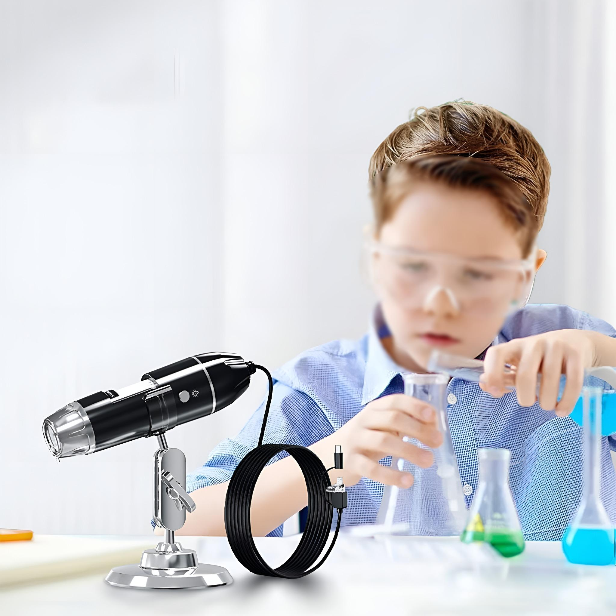 Ein Junge mit Schutzbrille mischt Chemikalien. Mikroskop und Kabel im Vordergrund, Bechergläser mit Flüssigkeiten im Hintergrund.