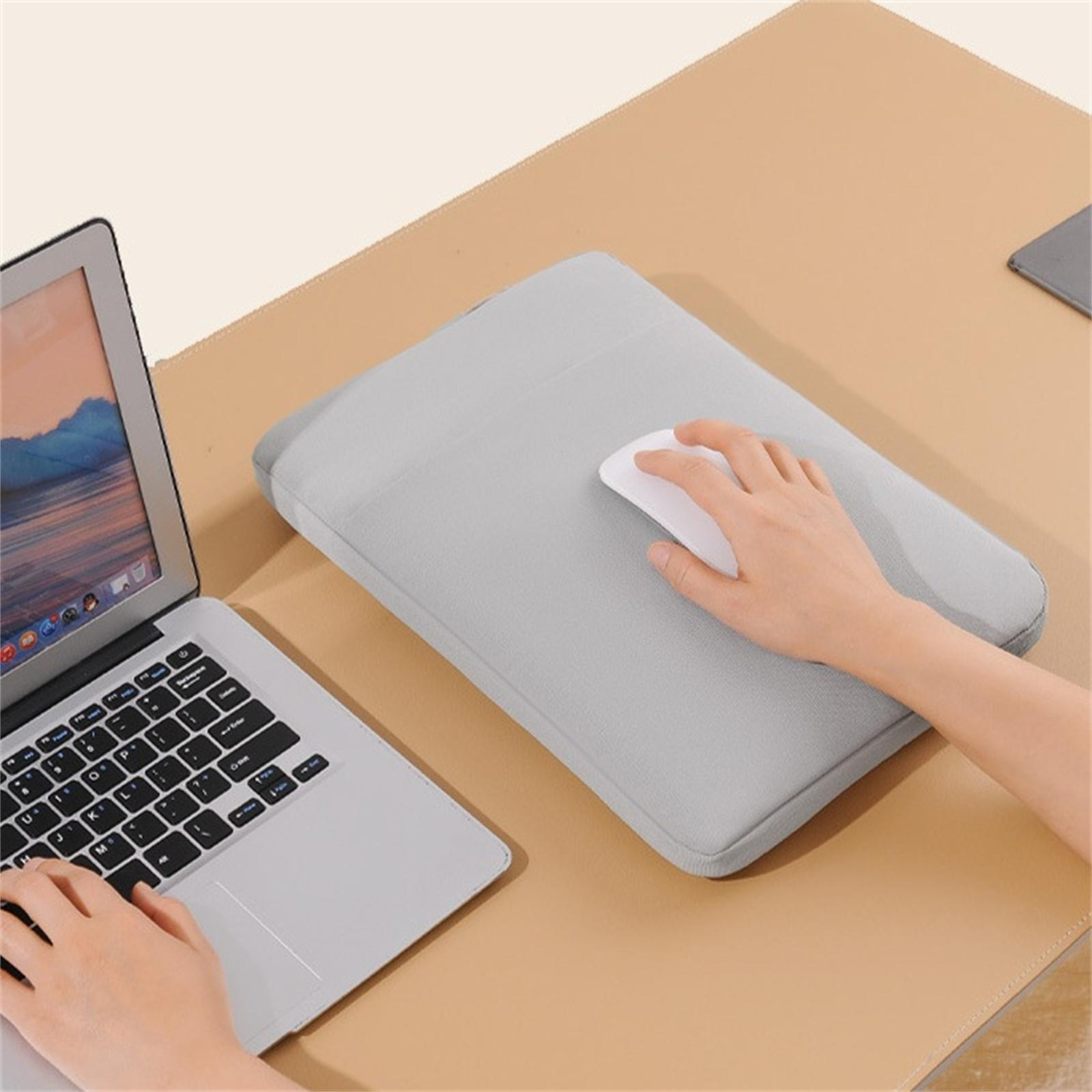 Hände auf Laptop-Tastatur und Maus auf grauer Laptoptasche auf beigem Schreibtisch.