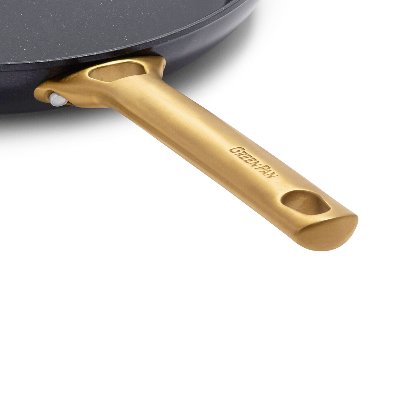 Nahaufnahme eines goldfarbenen Pfannengriffs, der an einer dunkelgrauen Pfanne befestigt ist. Der Griff trägt den Schriftzug 'GreenPan'.