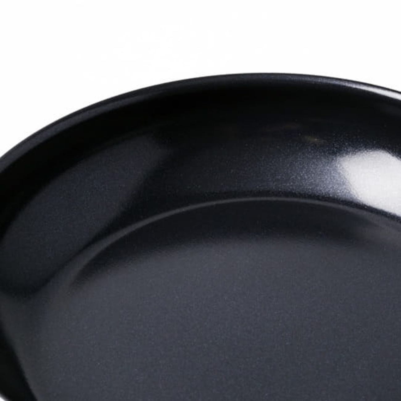 Nahaufnahme einer schwarzen Bratpfanne. Die Pfanne ist rund und die Oberfläche hat ein glänzendes Finish. Der Hintergrund ist weiß.