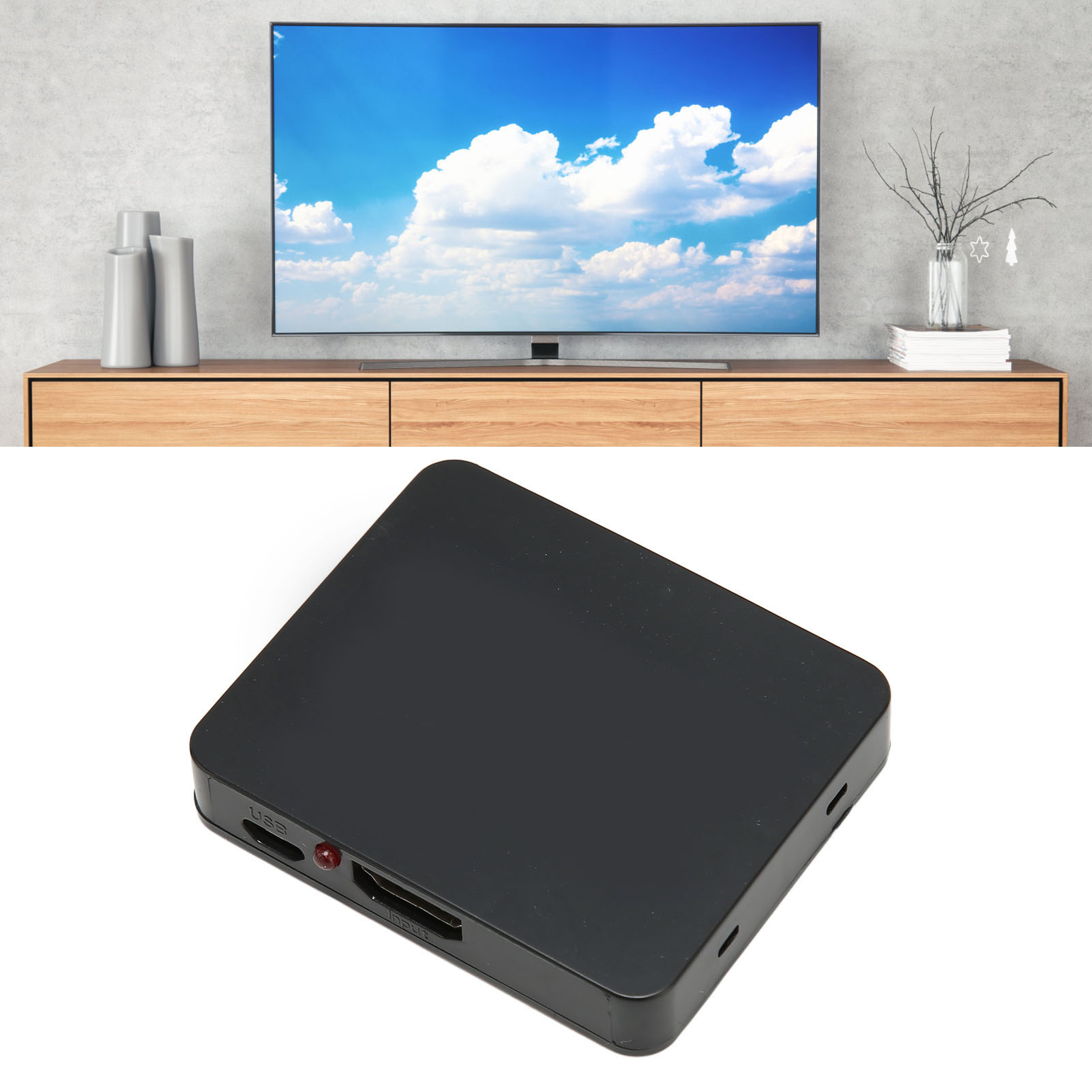 Ein schwarzer Mediaplayer liegt auf einer weißen Oberfläche. Ein Fernseher zeigt einen blauen Himmel mit Wolken. Darunter ein Holzschrank.