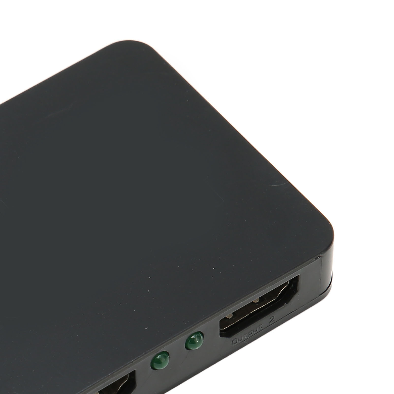 Ein schwarzes elektronisches Gerät mit HDMI-Anschlüssen und grünen Kontrollleuchten. Der Hintergrund ist weiß, das Gerät liegt flach.