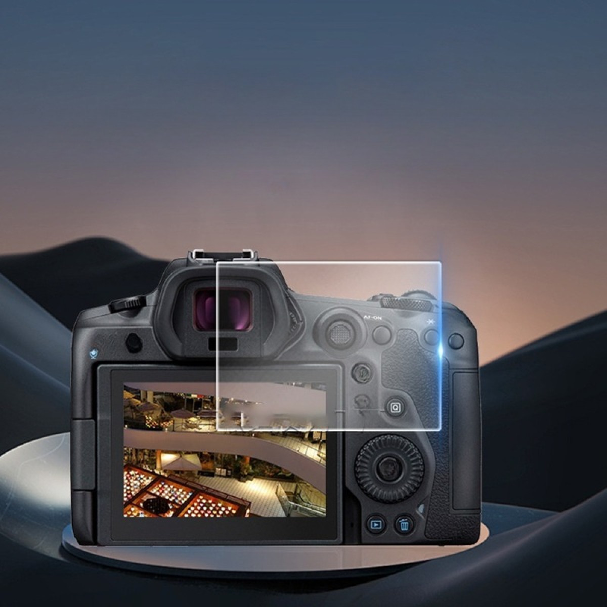 Una fotocamera nera mostra una scena interna con luci. È su una superficie riflettente, con uno sfondo sfocato.