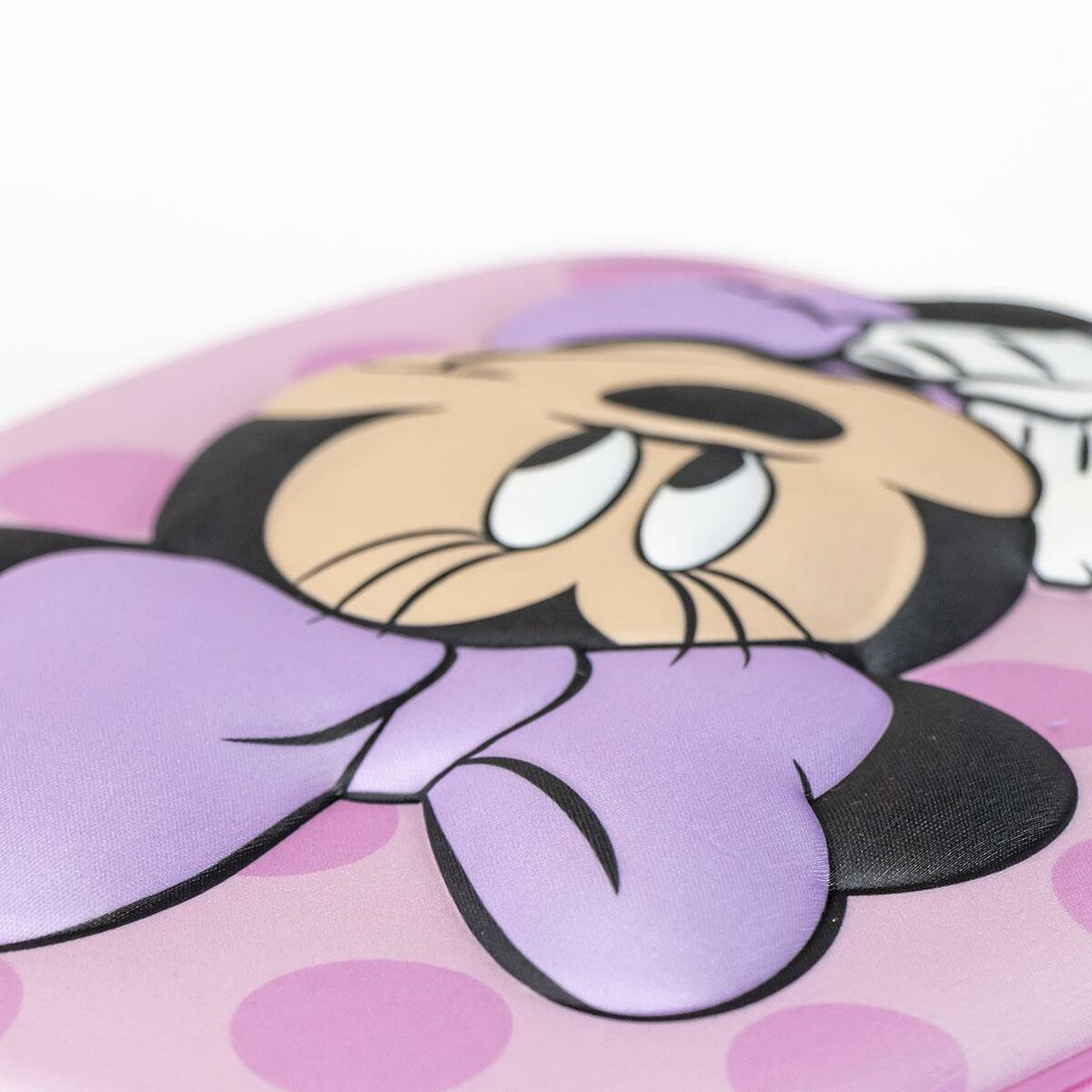 Nahaufnahme von Minnie Mouses Gesicht auf einer rosa Pünktchenoberfläche. Merkmale: lila Schleife und schwarze Umrisse. Weißer Hintergrund.