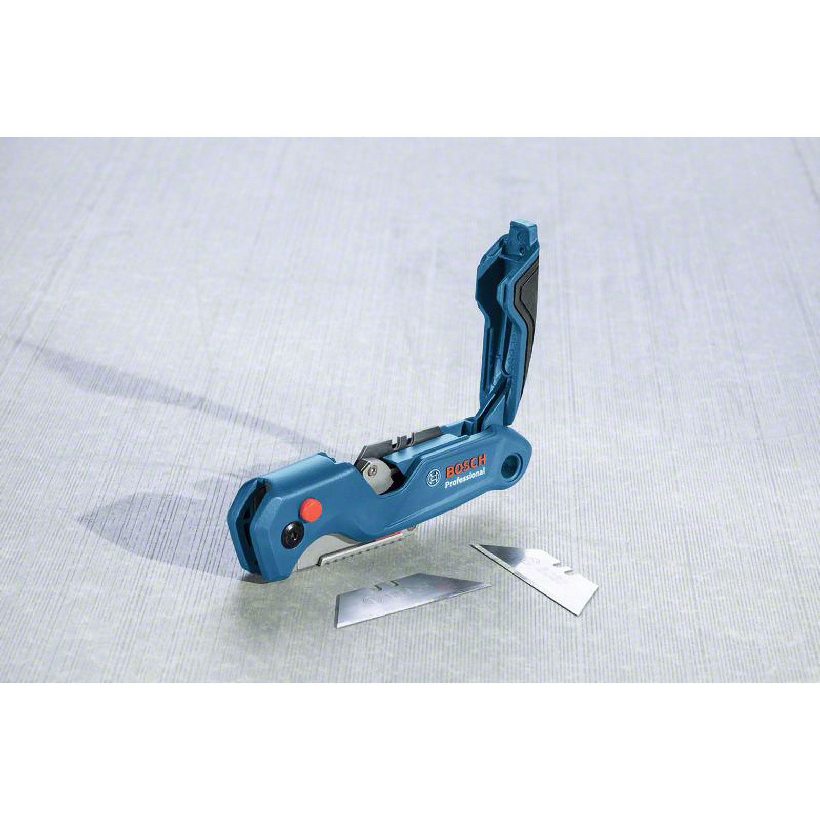 Blaues Bosch-Universalmesser mit offener Klinge, zwei Ersatzklingen auf grauer Oberfläche. Schwarze und rote Details. Bosch Professional.