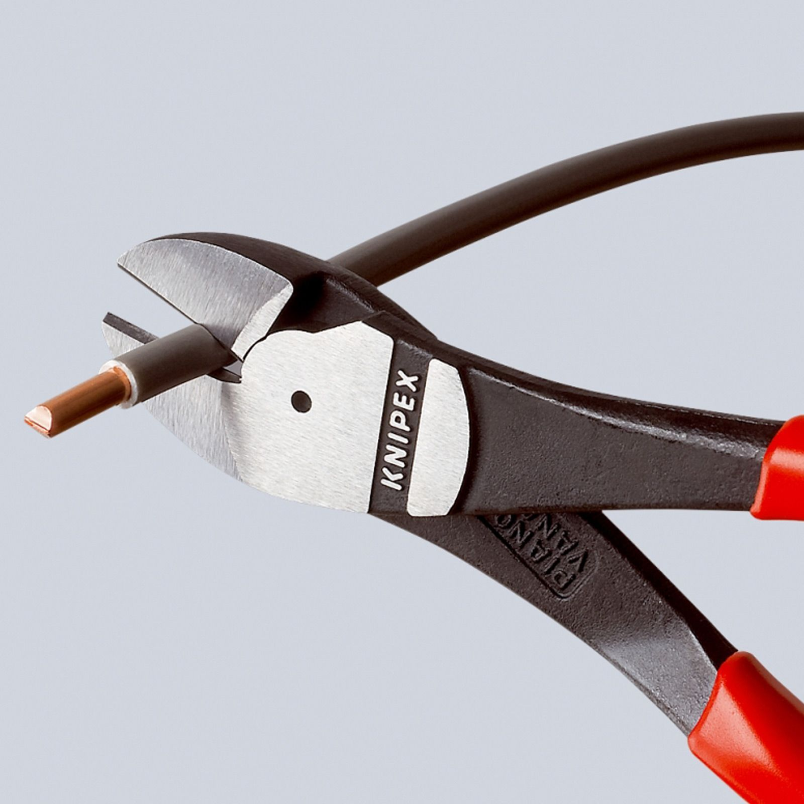 Zange schneidet ein Kabel. Die Zange ist schwarz mit roten Griffen. Das Kabel hat Kupfer und graue Isolierung.