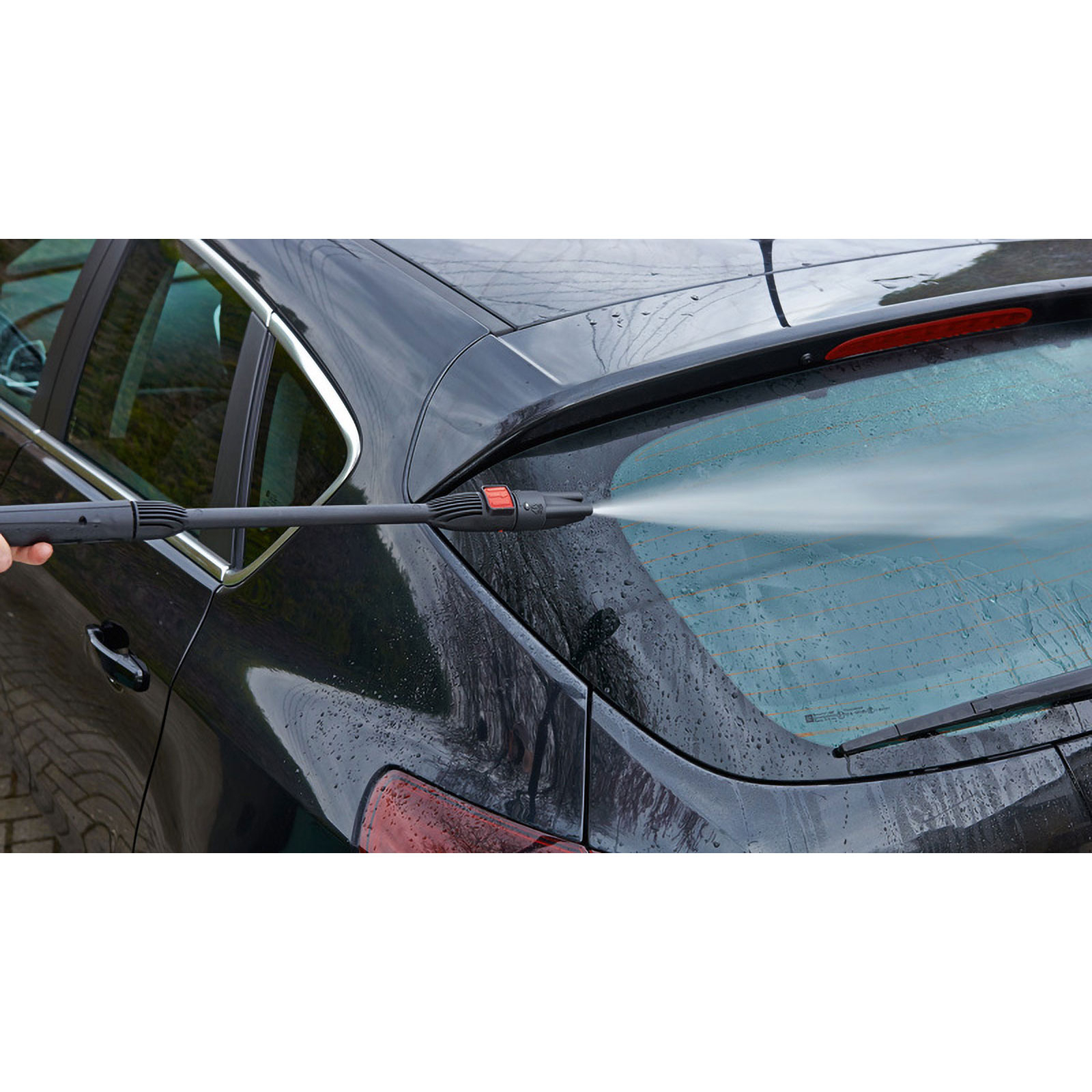 Ein schwarzes Auto wird mit einem Hochdruckreiniger gewaschen. Wasser spritzt über die Heckscheibe.