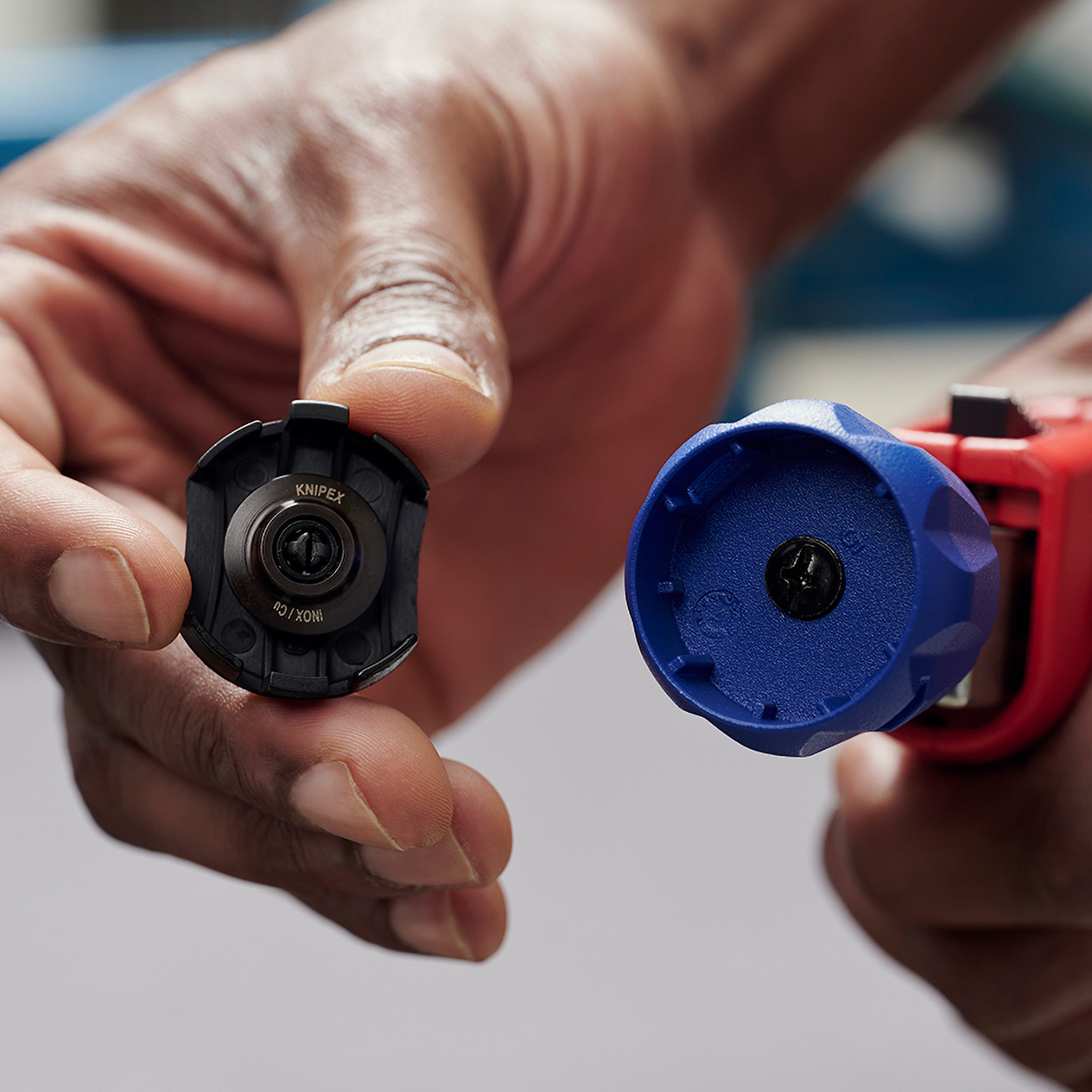 Mani che tengono un pezzo di utensile Knipex nero e un tagliatubi blu e rosso. Gli utensili sono nuovi.