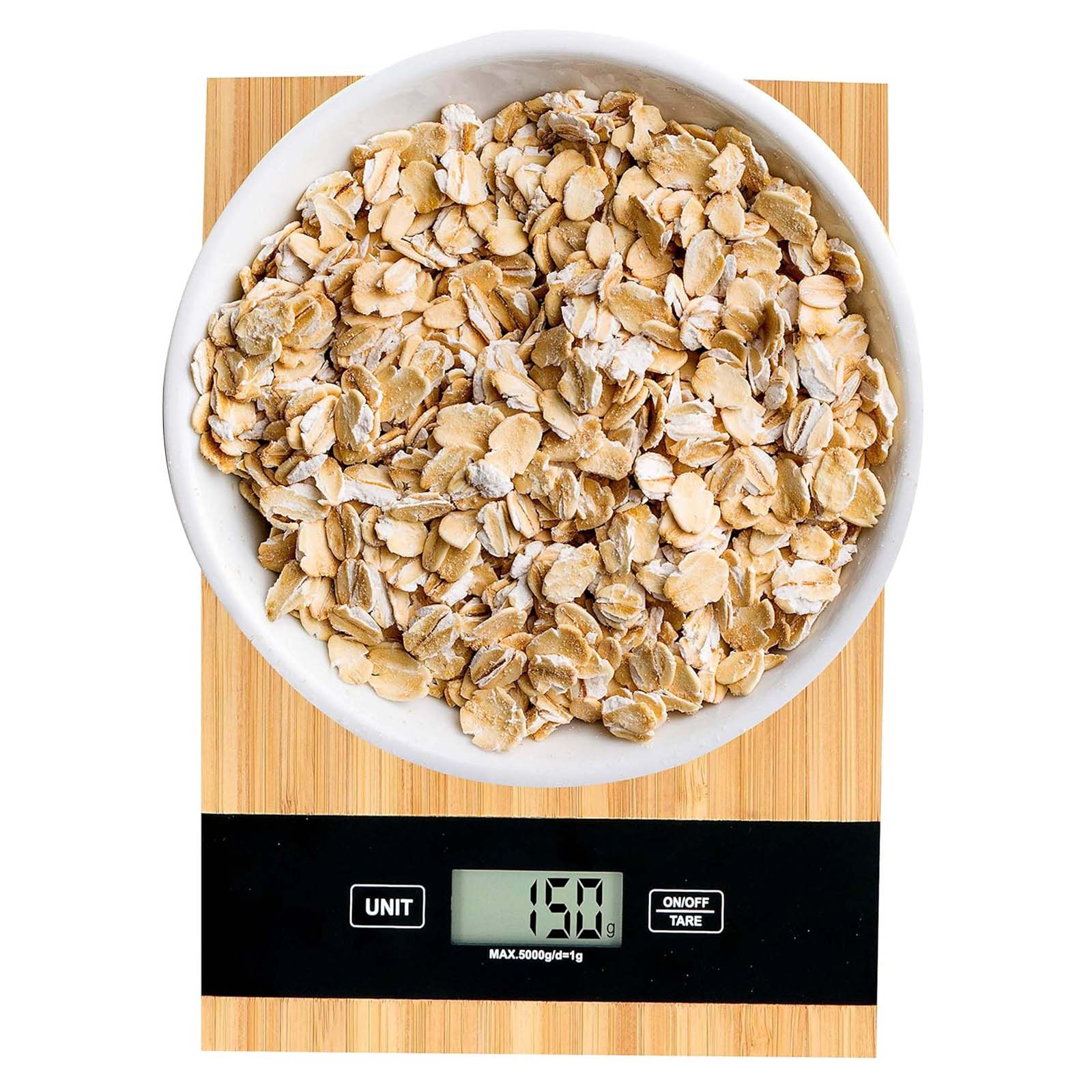 Eine weiße Schüssel mit Haferflocken steht auf einer Holzoberfläche. Darunter befindet sich eine Digitalwaage mit 150g.