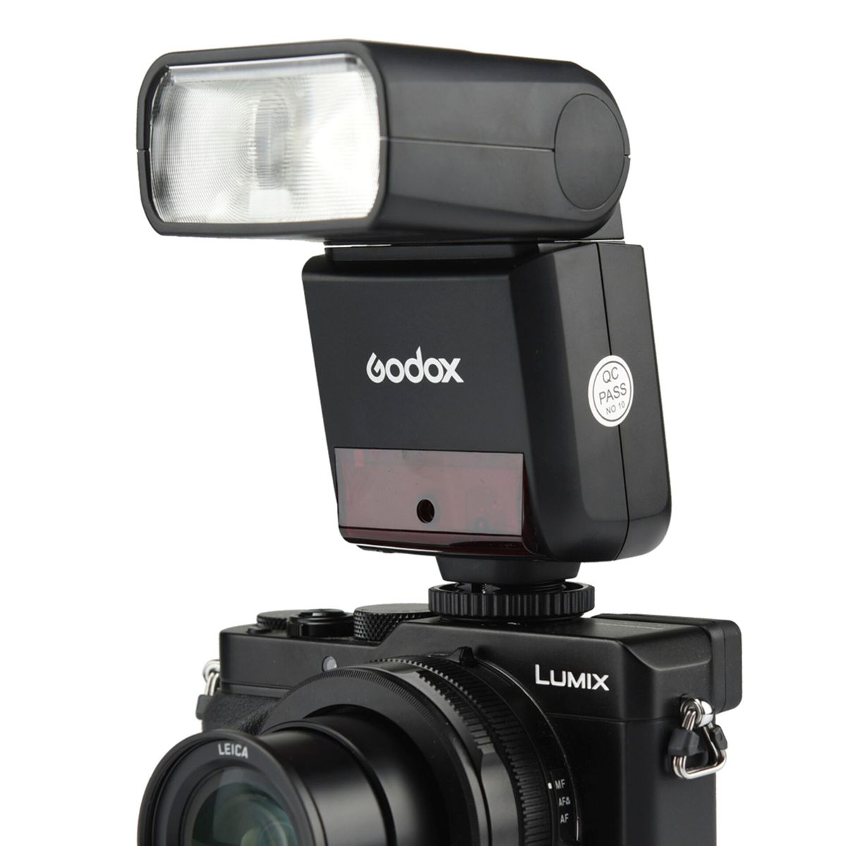 Un appareil photo noir avec un flash attaché. Le flash a un logo Godox. L'appareil photo a un objectif Leica et la marque Lumix.
