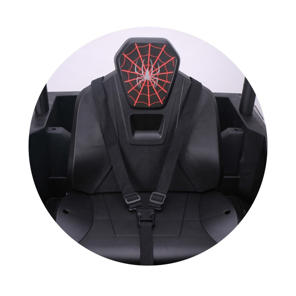 Asiento de coche negro con diseño de telaraña roja en el reposacabezas. Cinturón de seguridad negro abrochado. El fondo es blanco.