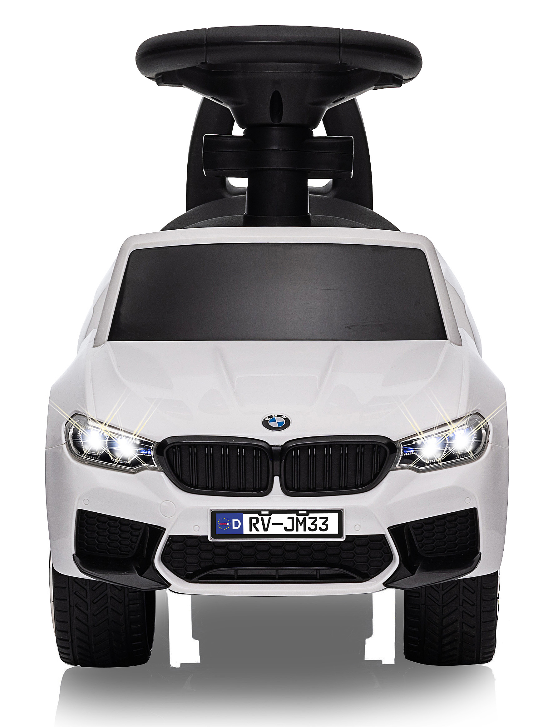 Ein weißes Spielzeugauto, das einem BMW ähnelt, mit schwarzen Akzenten und einem Lenkrad. Das Auto hat helle Scheinwerfer und ein Kennzeichen.