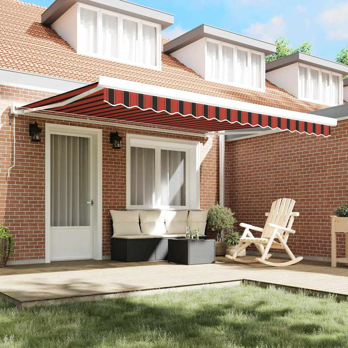 Una casa con una tenda a strisce rosse. C'è un ponte di legno con mobili, una sedia a dondolo e un muro di mattoni.