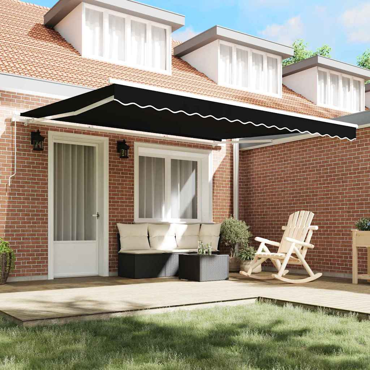 Eine schwarze Markise über einer Terrasse mit einer weißen Tür, einer Bank, einem Schaukelstuhl und einer Backsteinmauer.