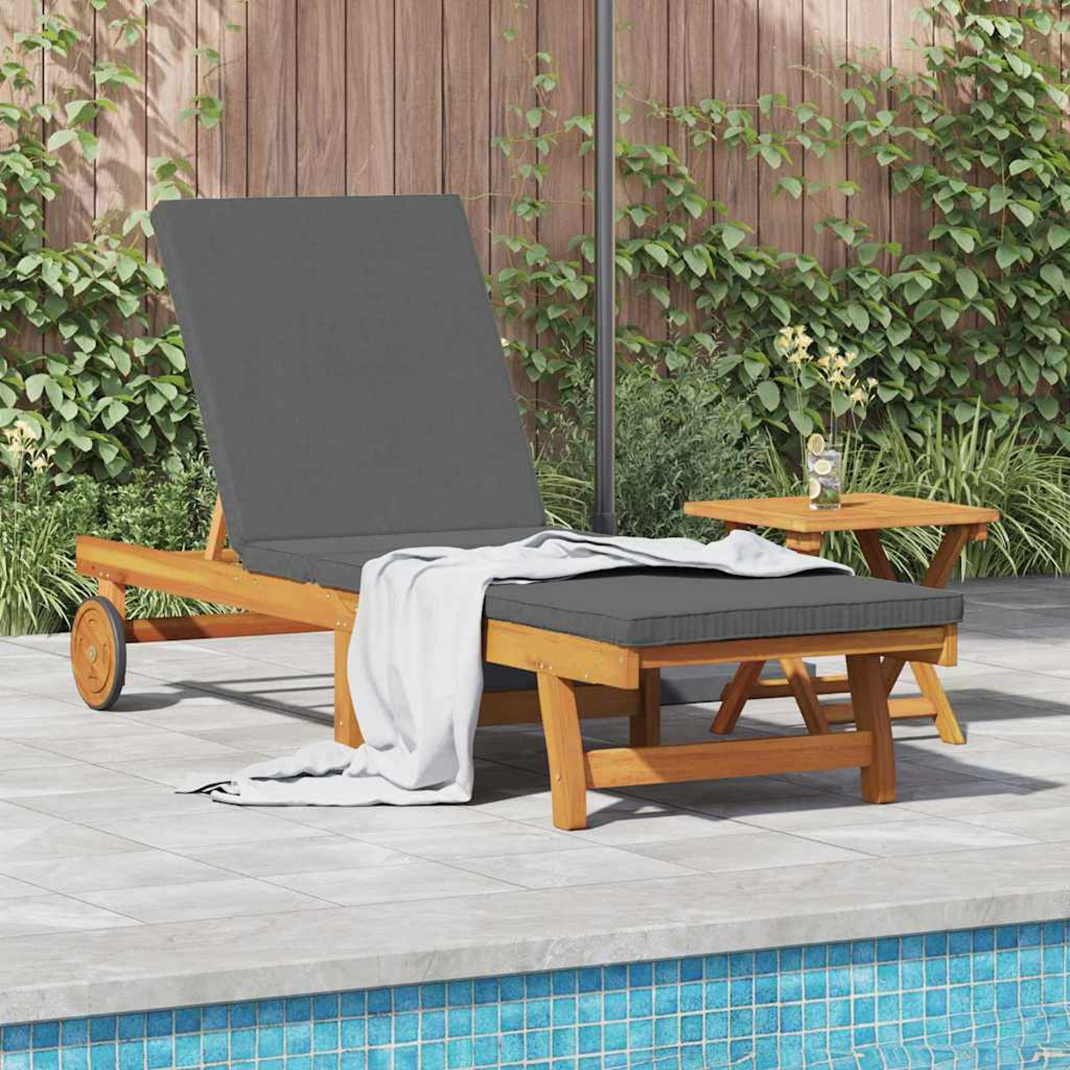 Eine Holzliege mit grauen Kissen und einem weißen Handtuch neben einem kleinen Tisch mit Blumen, in der Nähe eines Pools.