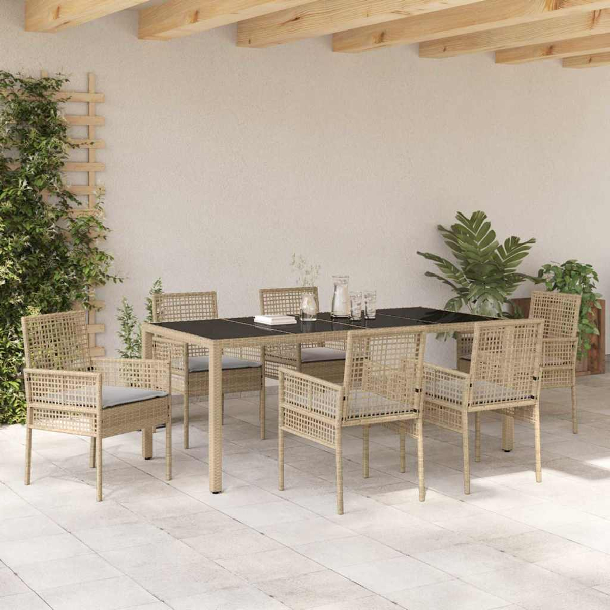 Essgruppe im Freien mit schwarzem Tisch und Korbstühlen. Pflanzen und eine Wand im Hintergrund. Sonniger Tag.