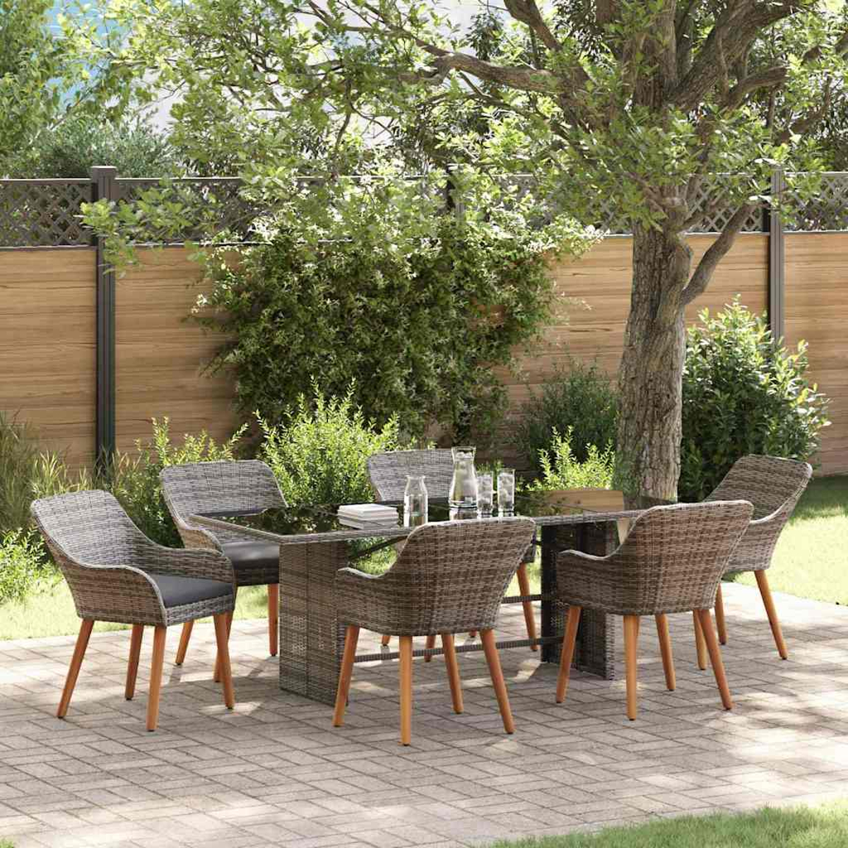 Essgarnitur im Freien mit sechs Stühlen, Tisch und Gläsern. Auf einer Backstein-Terrasse mit Baum und Holzzaun im Hintergrund.
