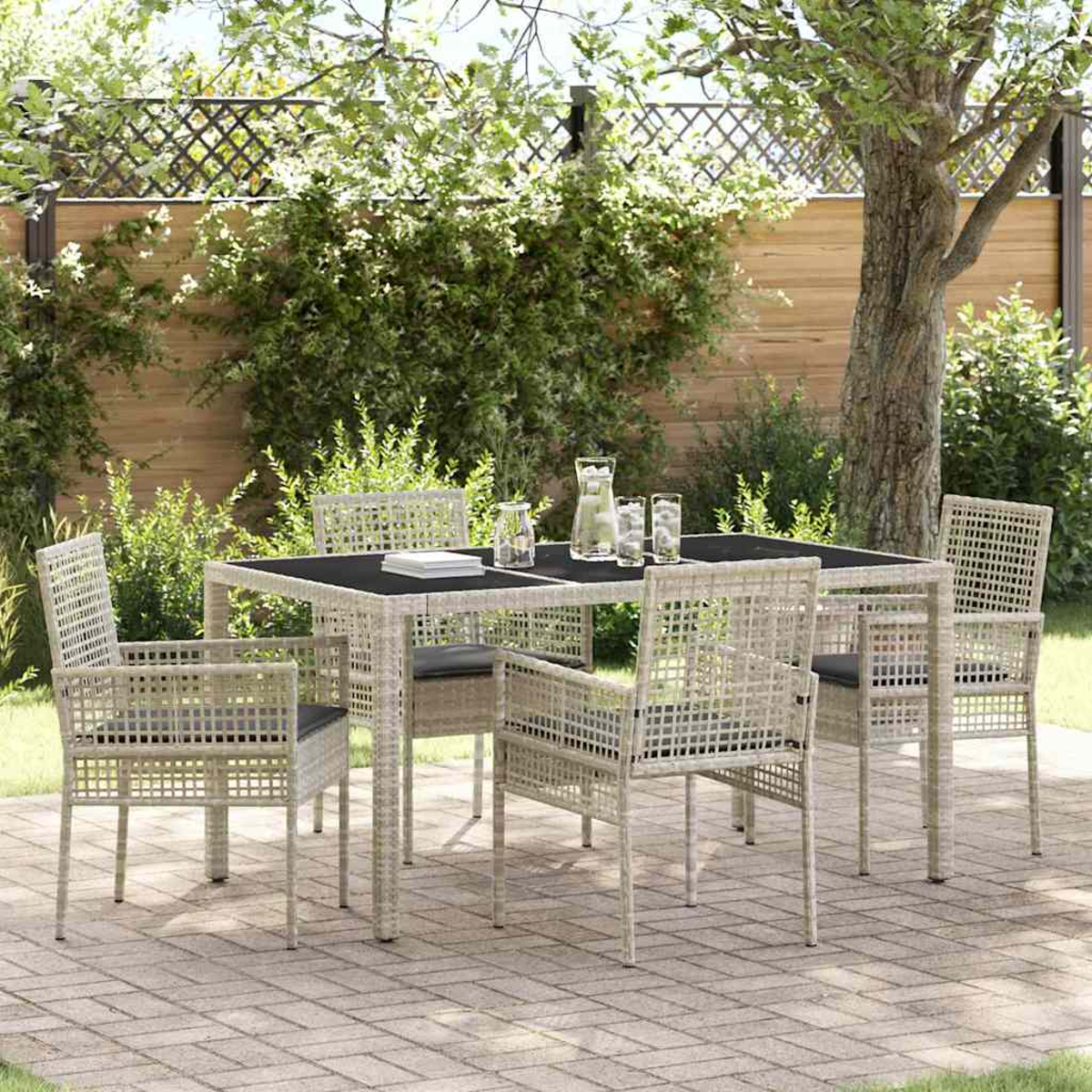 Eine Terrassengarnitur mit Tisch und sechs Stühlen. Der Tisch hat eine schwarze Platte mit Gläsern und einem Krug. Die Stühle haben graue Kissen.