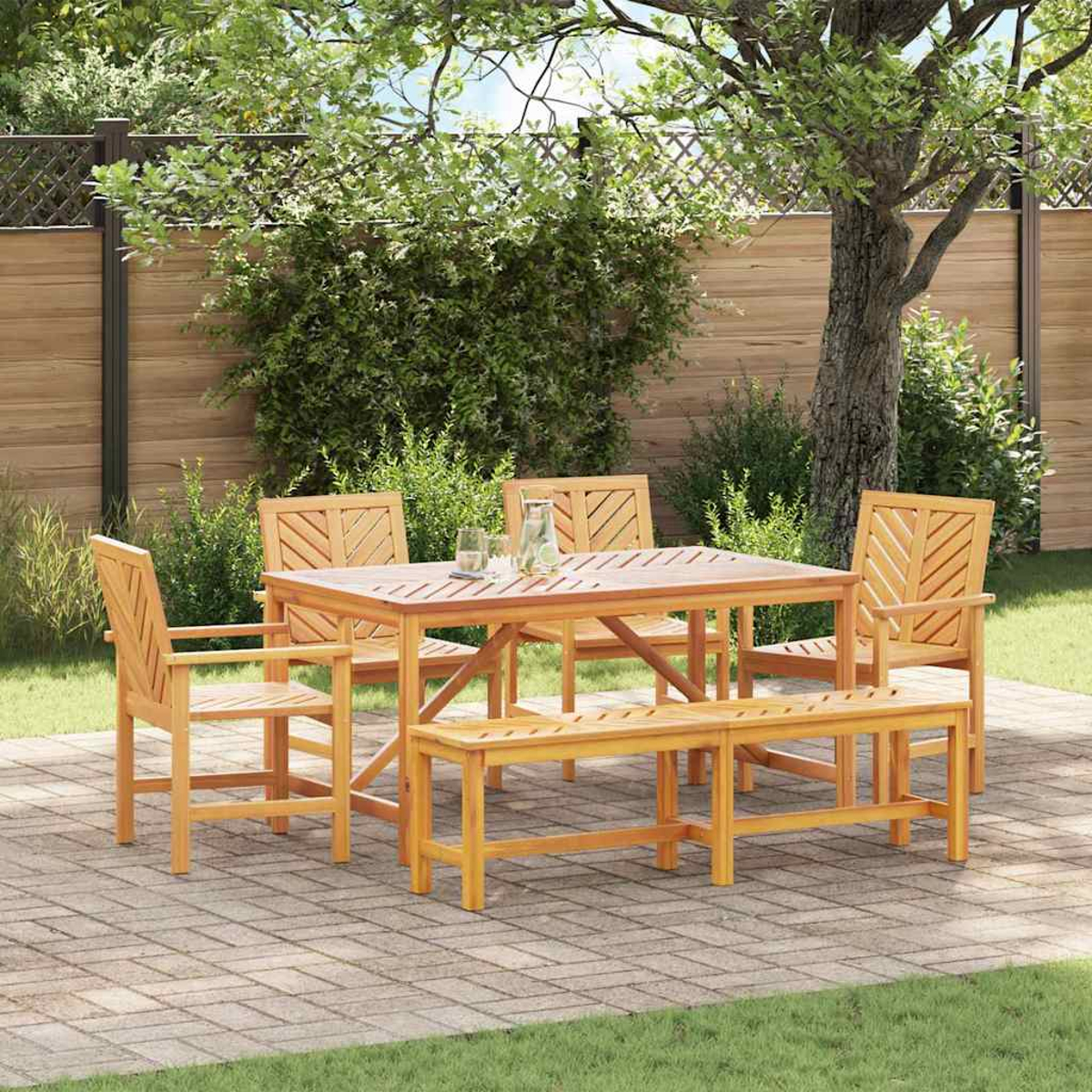 Essgruppe aus Holz im Freien: Tisch, Stühle und Bank auf einer Ziegelterrasse unter einem Baum, mit Holzzaun im Hintergrund.