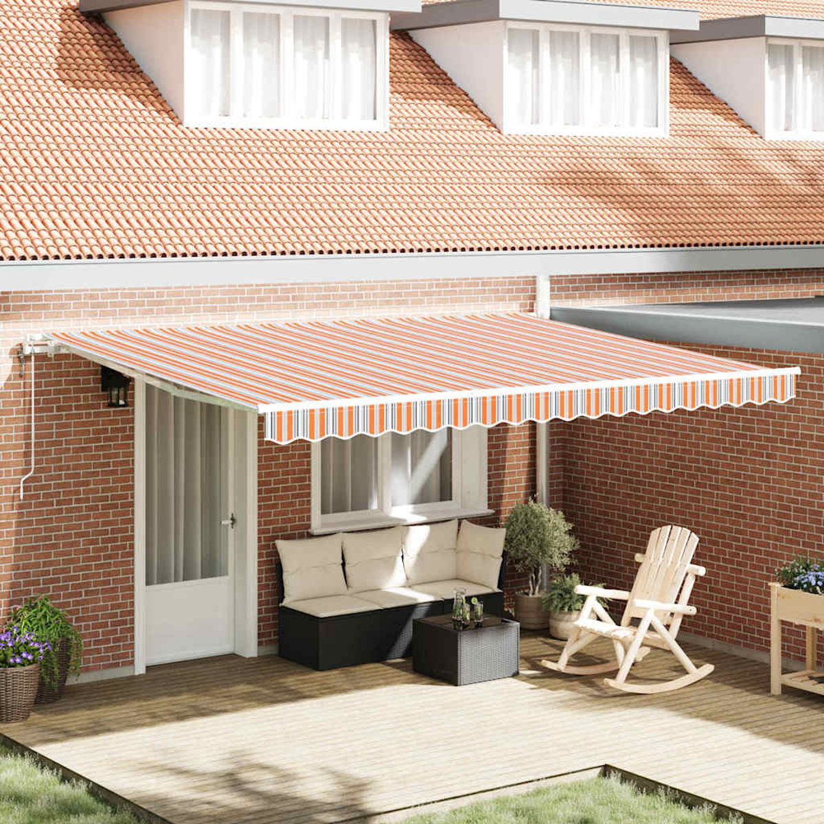 Außenansicht. Ein Backsteingebäude hat eine gestreifte orange-weiß Markise. Auf der Terrasse befinden sich Sofa, Tisch, Schaukelstuhl und Pflanzen.