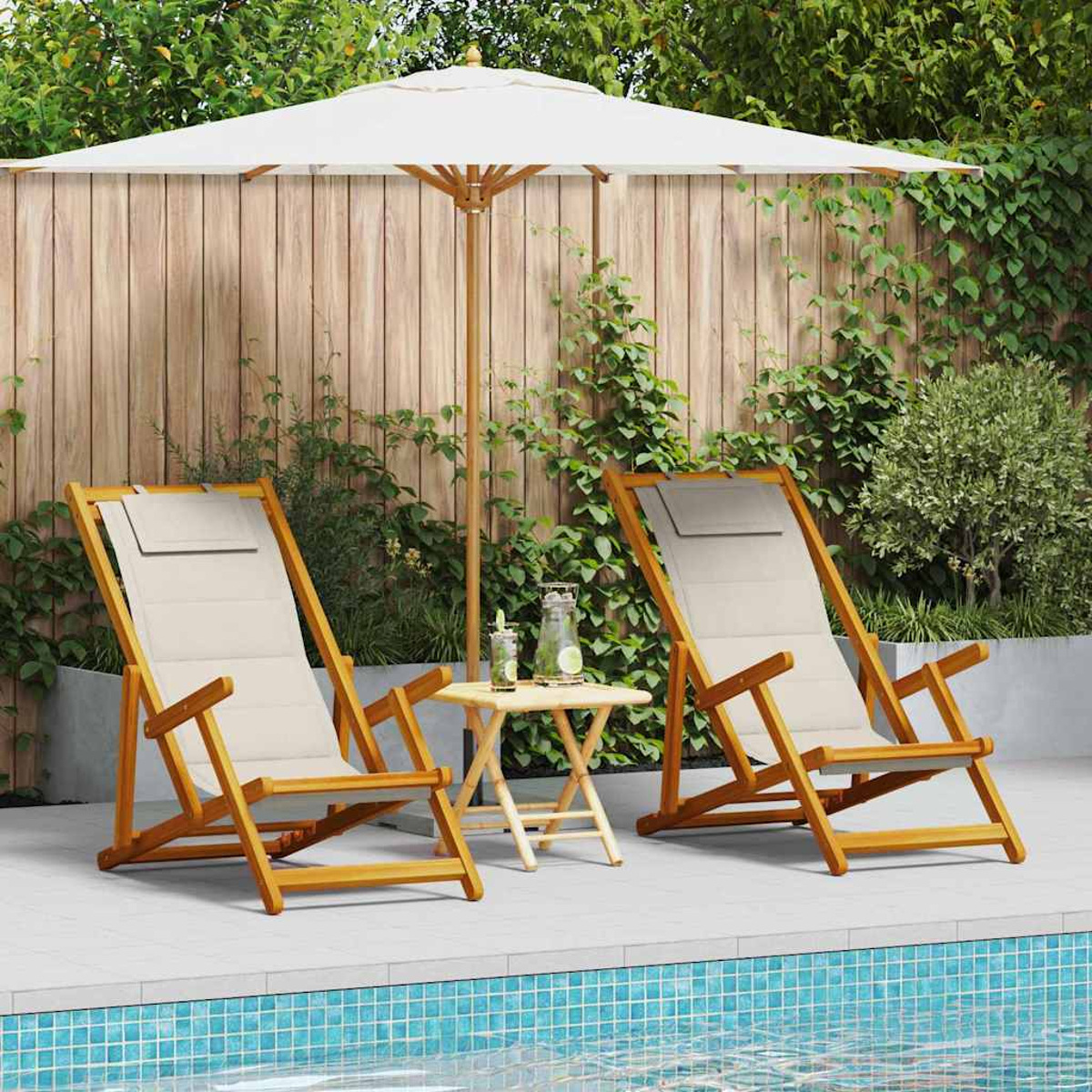 Dos tumbonas de madera cerca de una piscina bajo una sombrilla blanca. Una mesa pequeña con bebidas y una valla de madera son visibles.