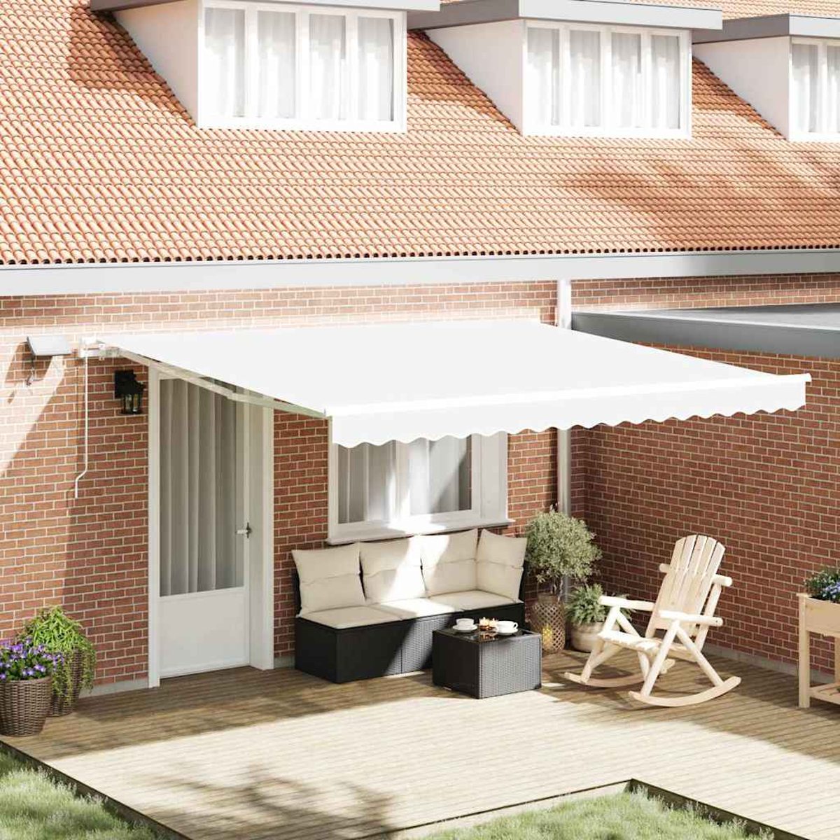 Eine weiße Markise erstreckt sich über einer Terrasse mit Sitzgelegenheiten, einem Tisch und einem Schaukelstuhl, vor einer Ziegelmauer und einem Ziegeldach.