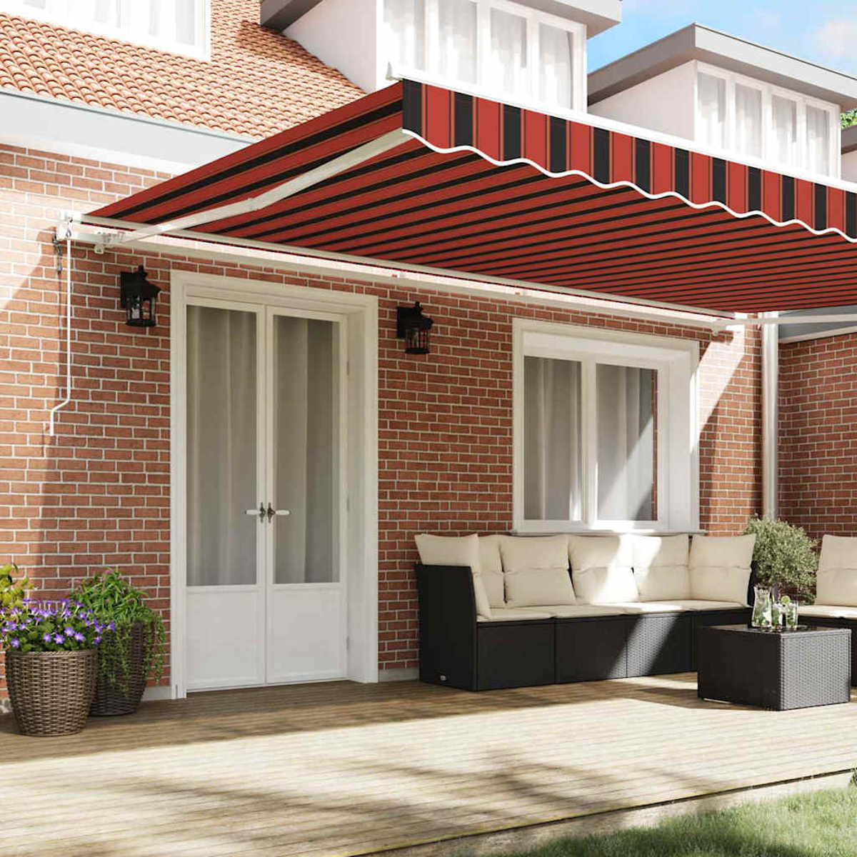 Außenansicht eines Hauses mit rot-schwarz gestreifter Markise. Eine Terrasse mit Möbeln und Pflanzen ist sichtbar.